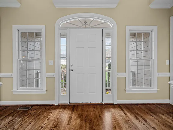 Bright entry hall with an arched transom, sidelights, and warm wood flooring