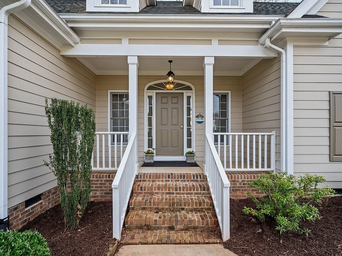 Covered front porch with brick steps, white railings, and a sheltered entry