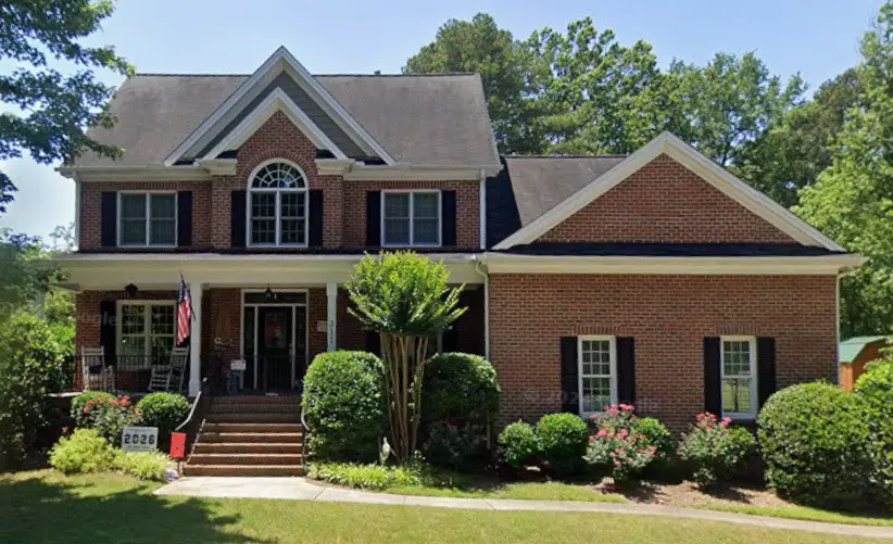 Traditional brick home with a covered front porch and landscaped lawn