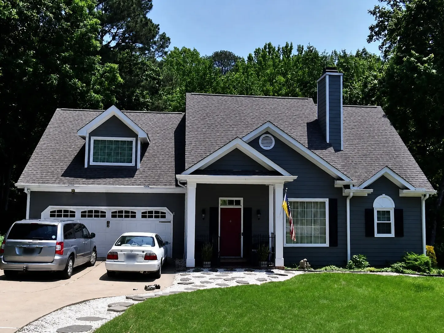 Charcoal cottage-style home with dormer, chimney, and red front door