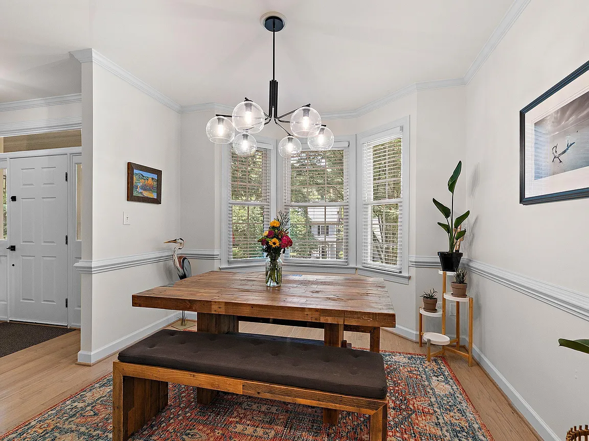Dining room with a bay window, modern globe chandelier, and a warm wood table