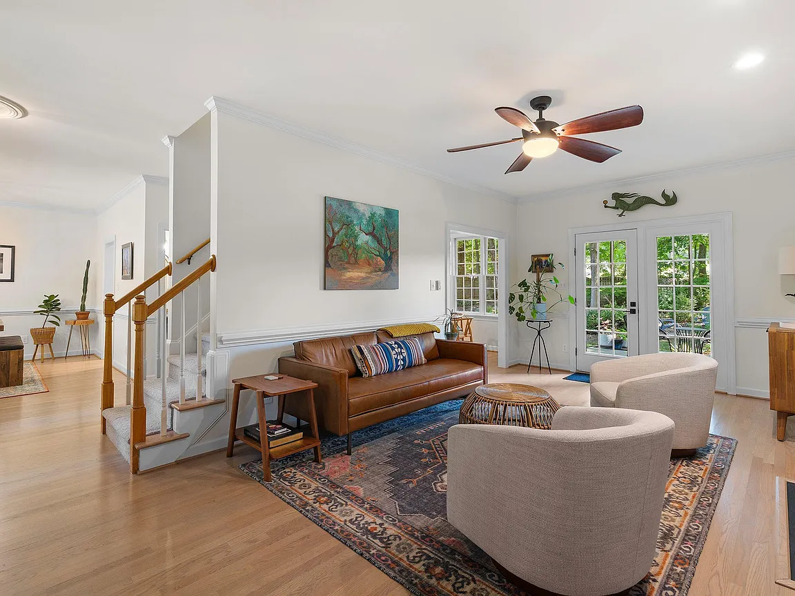 Open great room with a leather sofa, lounge chairs, French doors, and a view toward the staircase