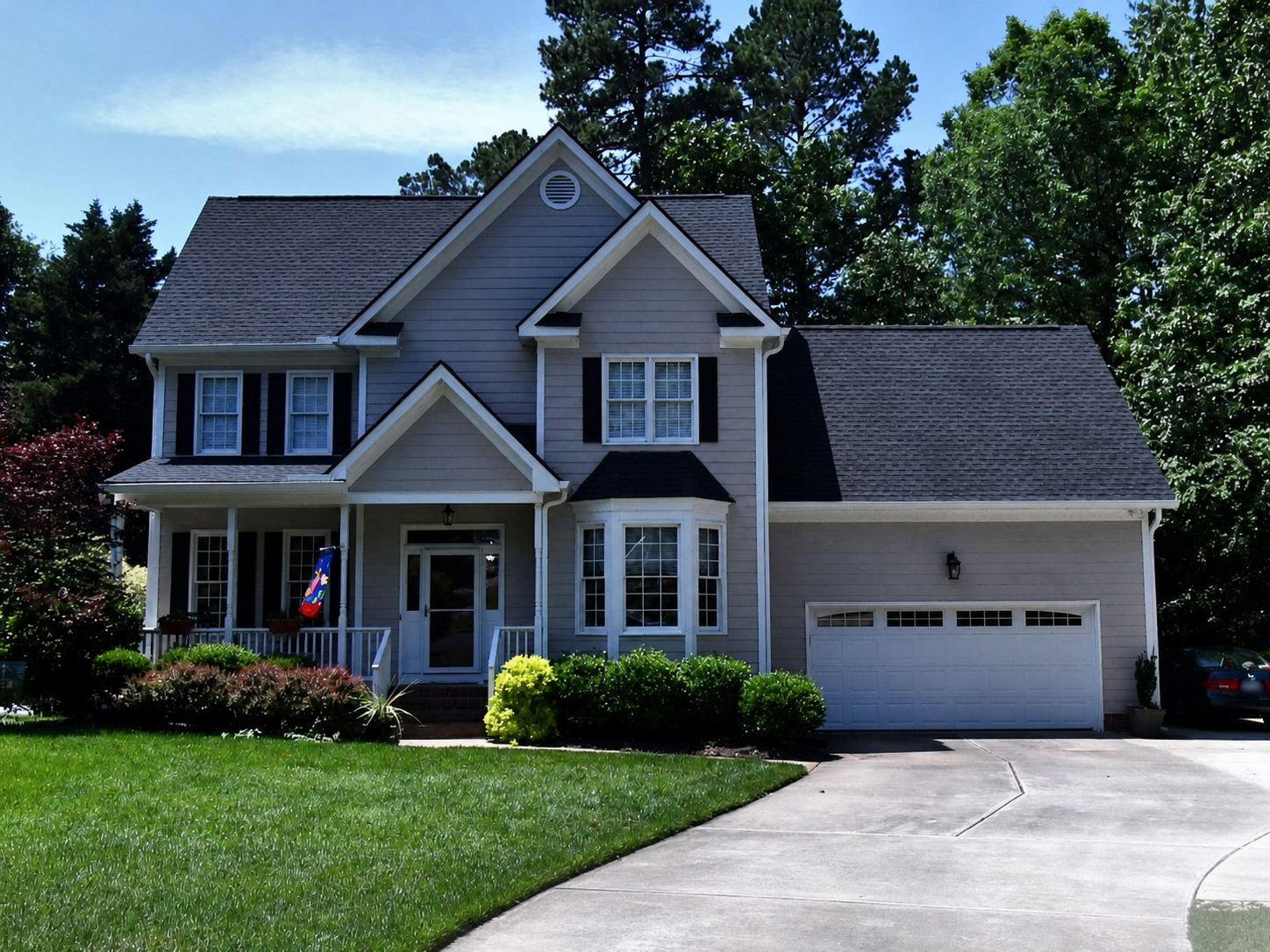 Gray two-story home with layered gables, a projecting bay window, and an attached garage