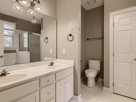 Bright bathroom with a double white vanity, glass shower, and neutral finishes