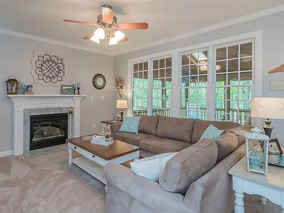 Living room with a white fireplace, broad windows, and soft neutral furnishings