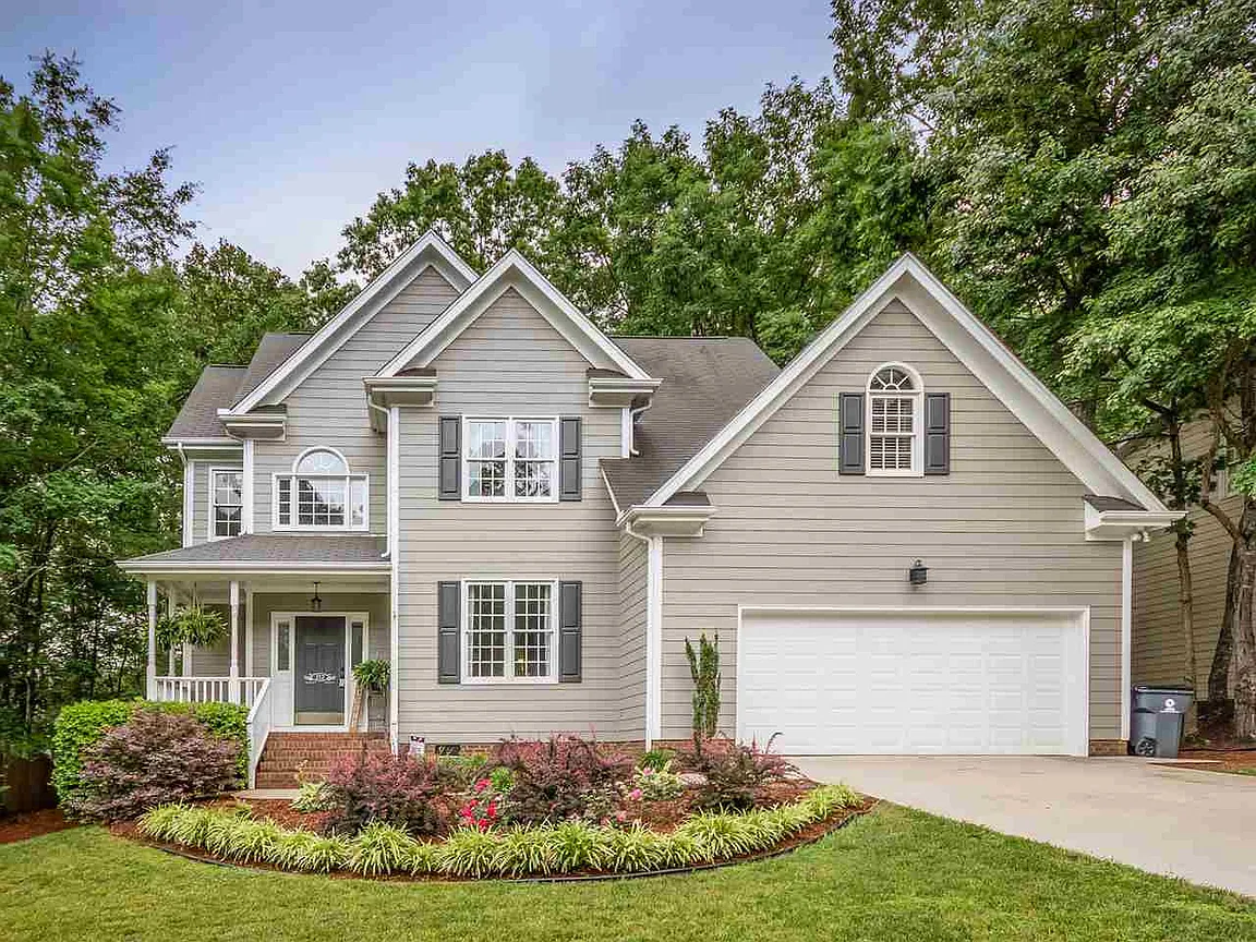 Two-story gray home with layered gables, white trim, and a landscaped front yard