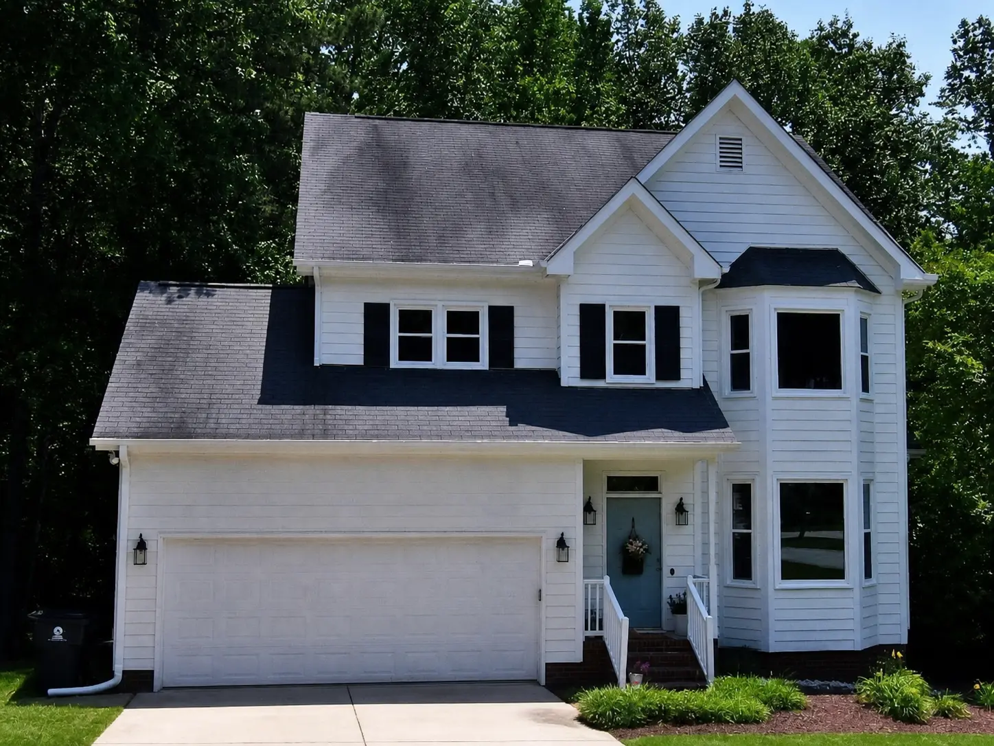 White two-story home with a tall bay window and attached garage