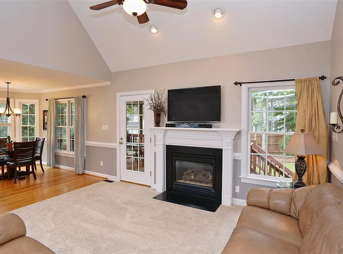 Family room with a white fireplace, vaulted ceiling, broad windows, and access to the screened porch