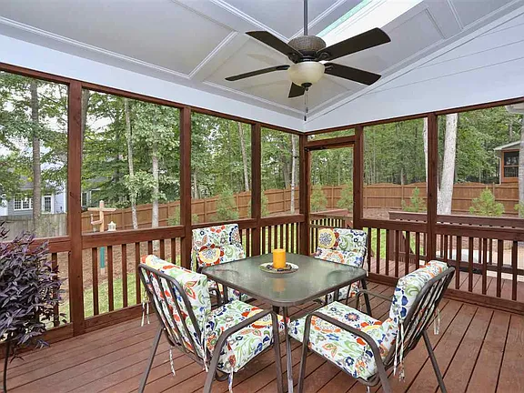 Screened wood porch with a paneled ceiling, ceiling fan, and wooded backyard views