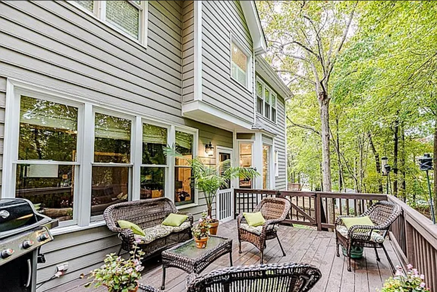 Wood deck with outdoor seating, broad windows, and views into the surrounding trees