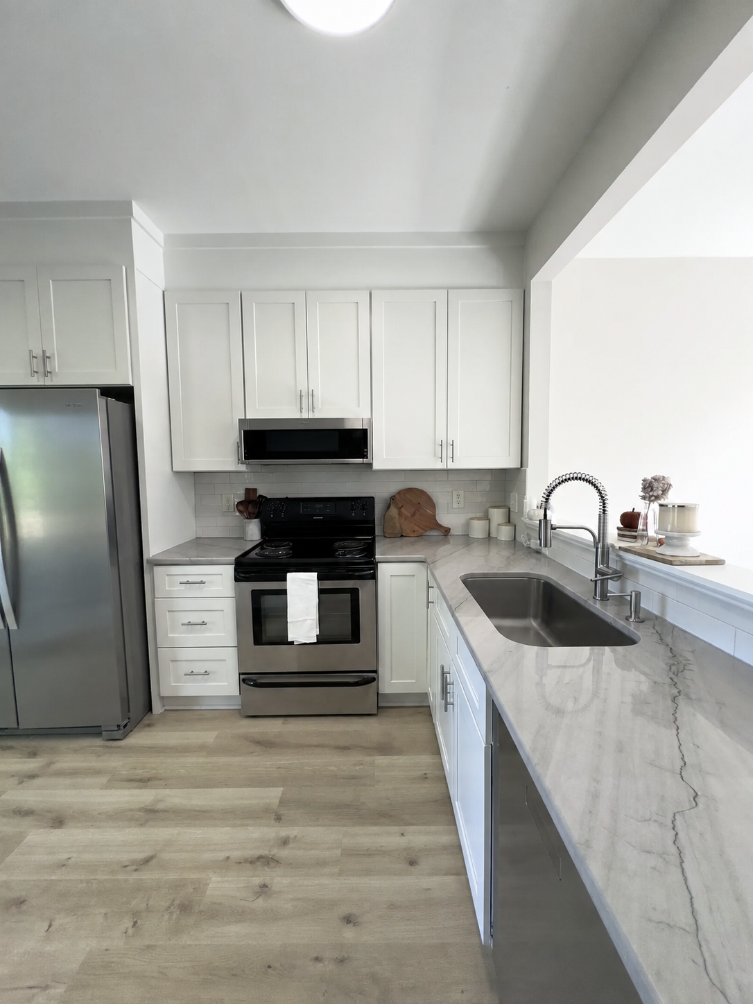White renovated kitchen with stainless appliances and marble-look counters