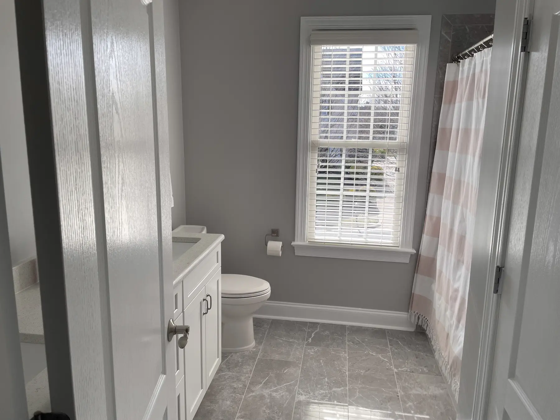 View into the bright family bathroom with gray tile flooring