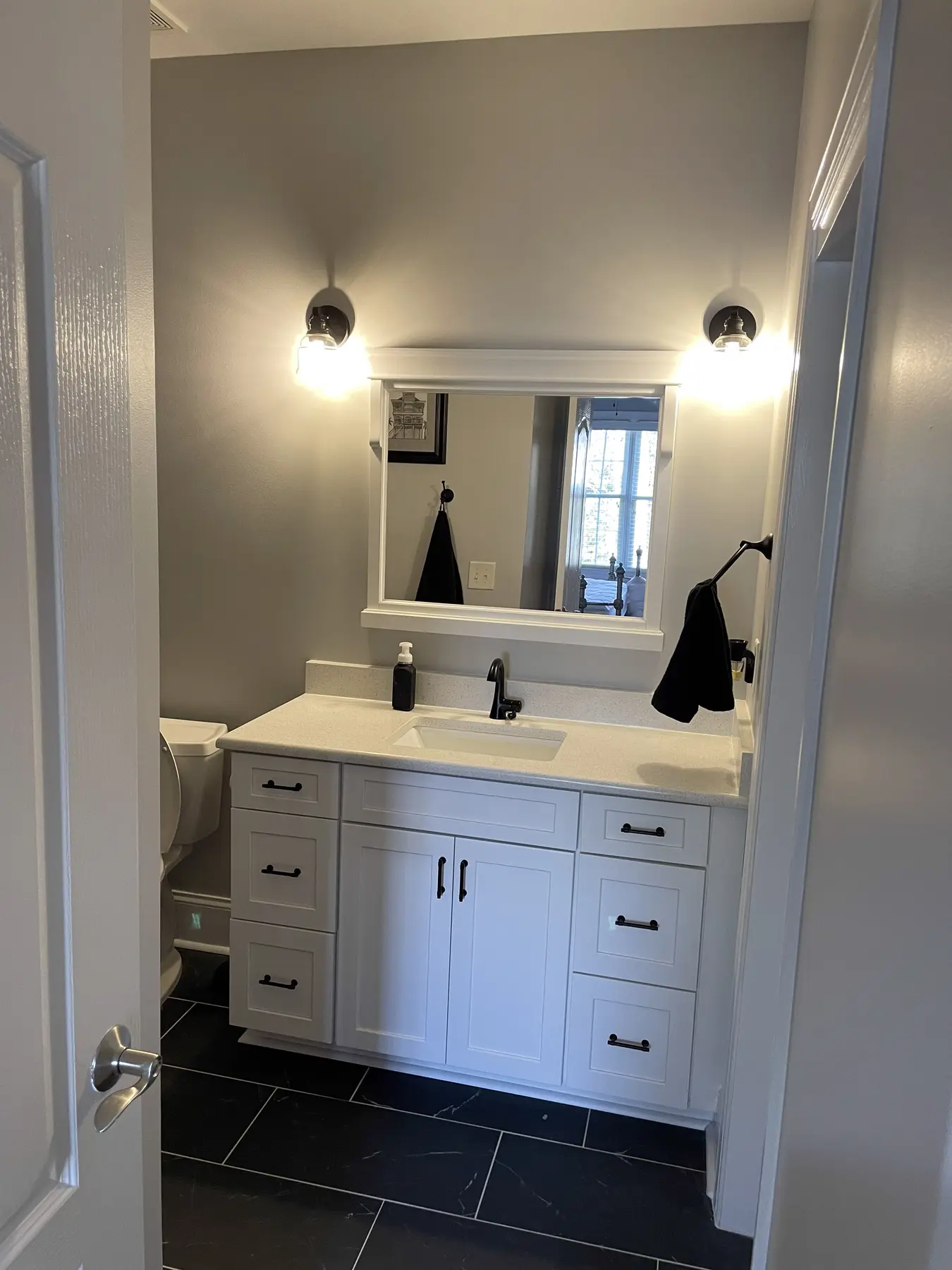 White vanity and mirror opposite the dark tiled shower