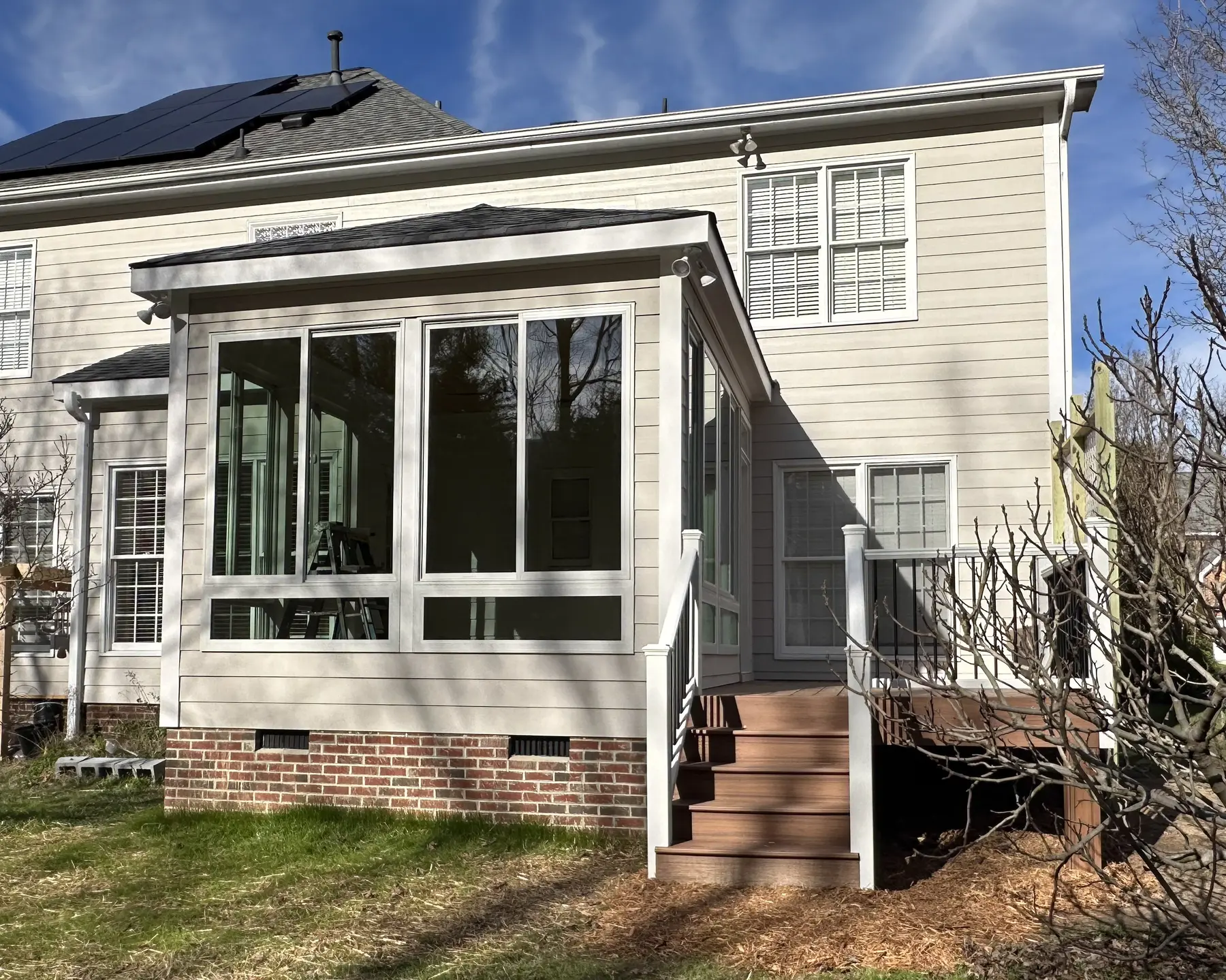 Completed sunroom addition attached to the rear of a two-story home