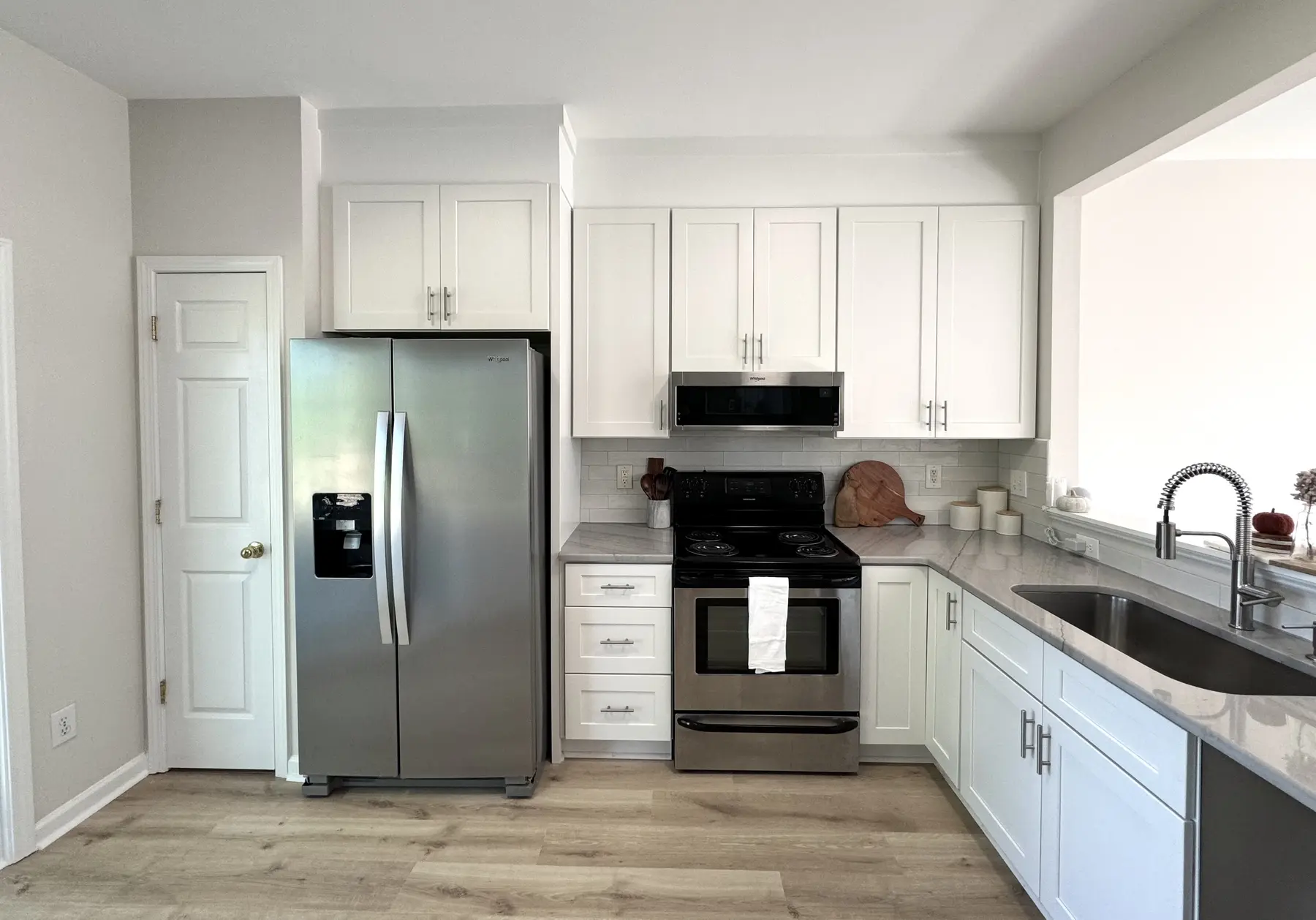 Bright renovated kitchen with white cabinetry and dark counters