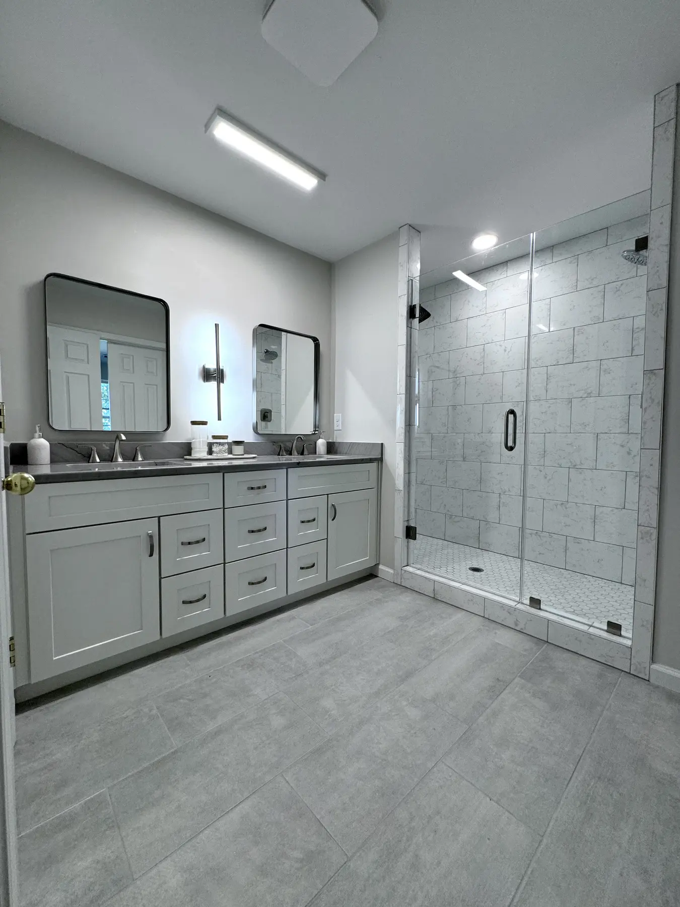 Gray primary bathroom with a glass shower and double vanity