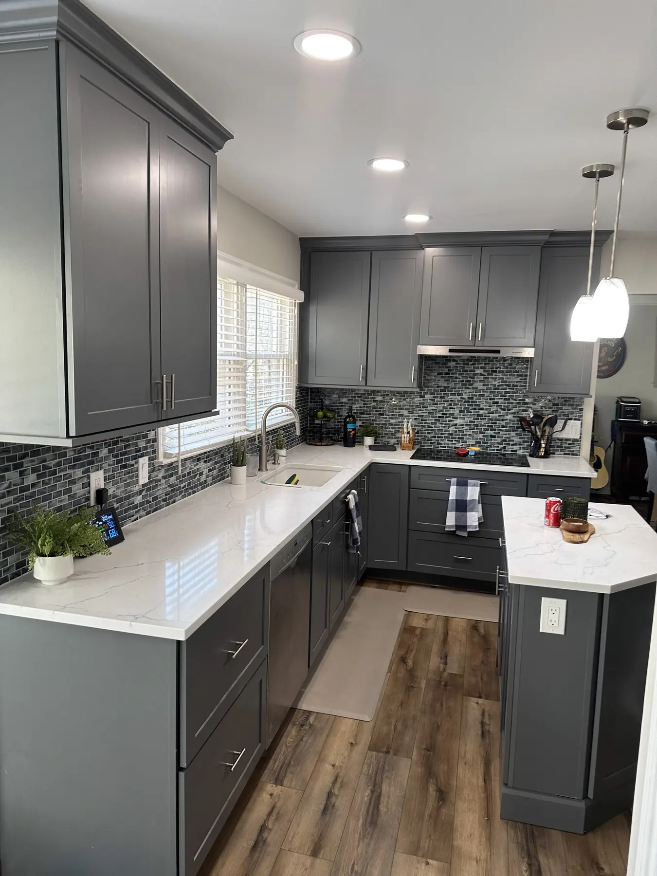 Gray kitchen cabinetry, island, and warm wood-look flooring