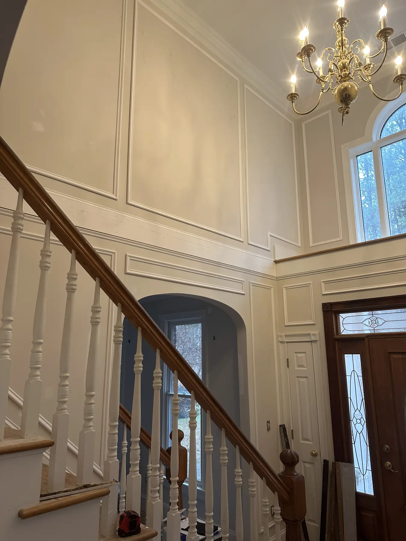 Two-story entry with custom white wall paneling and refinished stair details