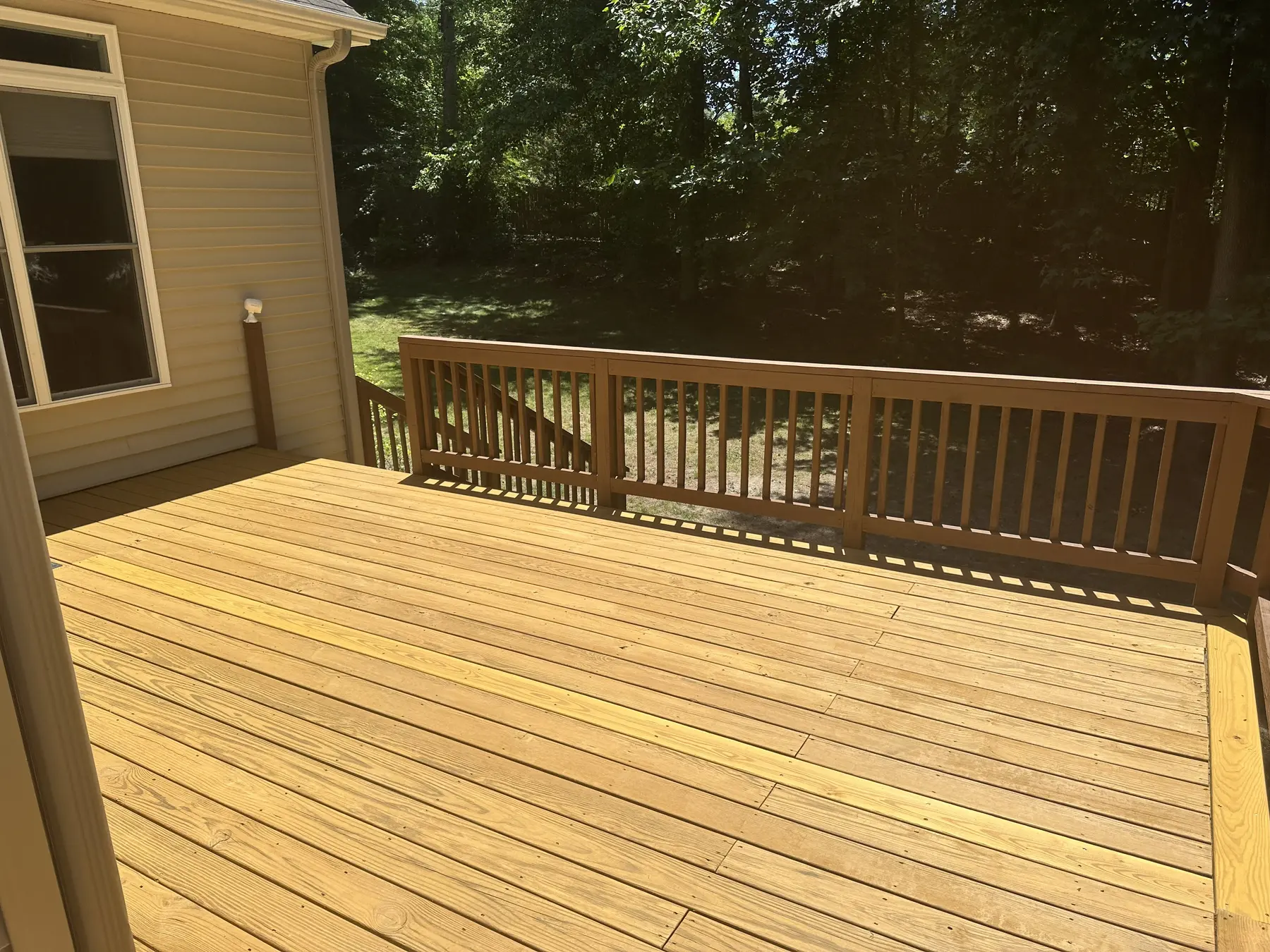 Fresh deck boards and railing overlooking the wooded yard