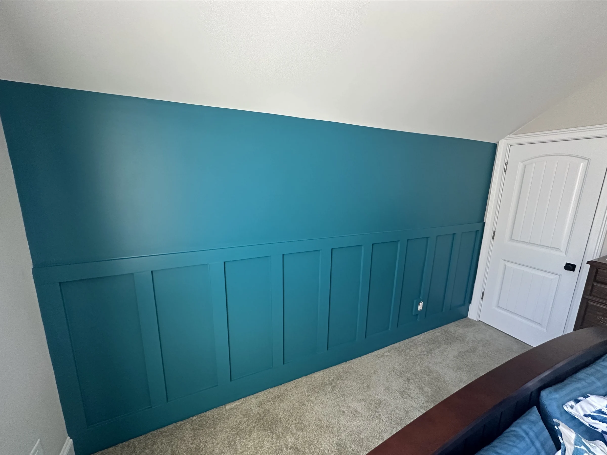 Deep blue bedroom feature wall with custom paneled wainscoting